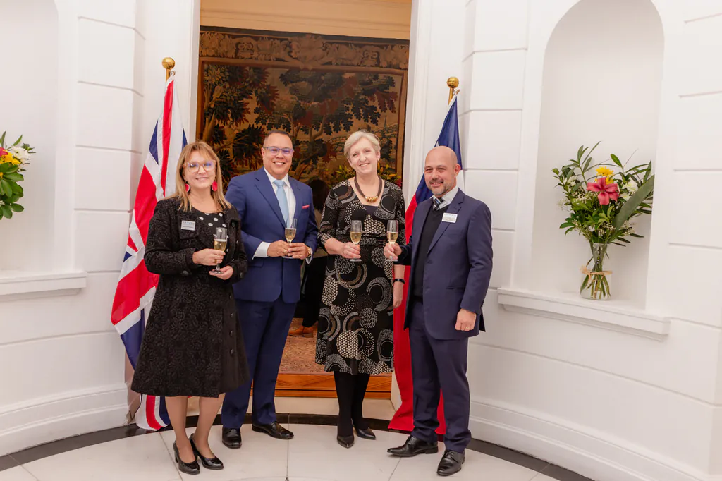 oxford-test-of-english-retrato-cuatro-invitados-banderas-embajada-britanica-santiago invitados posando en evento de oxford university en la embajada británica